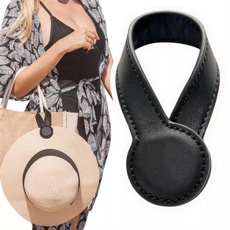 Black magnetic hat clip holding a hat on a bag